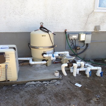 Pool equipment pad with heater, filter, and electrical boxes.