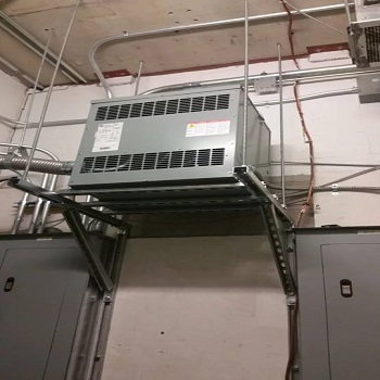 Industrial transformer unit mounted above breaker panels.