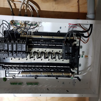 Electrical panel with breakers and wiring installed in a metal enclosure.