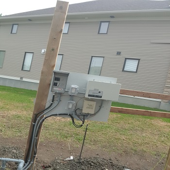 Temporary electrical service panel mounted on wooden post outdoors.
