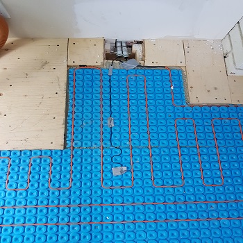 Radiant floor heating repair showing exposed subfloor and heat cables.