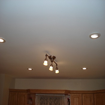 Kitchen ceiling with recessed lighting and three-light fixture.