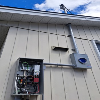 Electrical meter base and open service disconnect mounted on exterior siding.