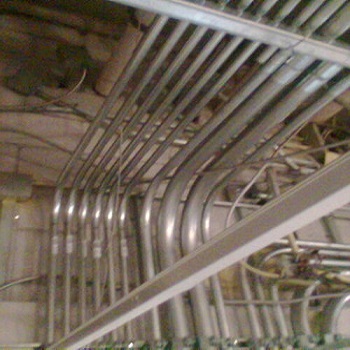 Industrial electrical conduit bends in ceiling.